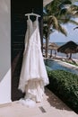 A wedding dress hangs on a hanger outdoors on a beach background Royalty Free Stock Photo