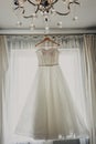 Wedding dress. White wedding dress with a full skirt on a hanger in the room of the bride with white curtains. Wedding Royalty Free Stock Photo