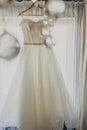 Wedding dress. White wedding dress with a full skirt on a hanger in the room of the bride with white curtains. Wedding Royalty Free Stock Photo