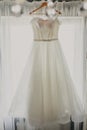 Wedding dress. White wedding dress with a full skirt on a hanger in the room of the bride with white curtains. Wedding Royalty Free Stock Photo