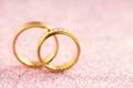 Wedding or Engagement background - pair of golden wedding rings on sparkle pink backdrop