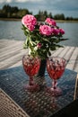 Wedding festive composition of a bouquet of pink flowers in a vase and wine in glasses on the table. Royalty Free Stock Photo
