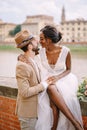 Wedding in Florence, Italy. Interracial wedding couple. An African-American bride is sitting on a brick wall and