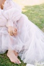 Bare feet of the bride on the grass, next to shoes and a bouquet. Wedding in Florence, Italy, in an old villa-winery.