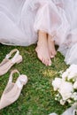 Bare feet of the bride on the grass, next to shoes and a bouquet. Wedding in Florence, Italy, in an old villa-winery.