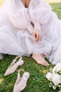 Bare feet of the bride on the grass, next to shoes and a bouquet. Wedding in Florence, Italy, in an old villa-winery.