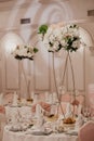 Wedding flowers decoration in the restaurant. Banquet round tables, decorated with a bouquet of white flowers in the center of the