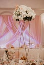 Wedding flowers decoration in the restaurant. Banquet round tables, decorated with a bouquet of white flowers in the center of the