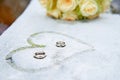 Wedding flowers, rings and painted heart on frozen surface