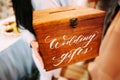 Wedding gifts. Bridesmaid holds wooden box with a handwritten sign. Present box for marriage