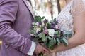 Wedding. The girl in a beige dress and a guy in a suit are holding a beautiful bouquet of white, purple, lilac flowers and greener Royalty Free Stock Photo