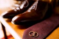 Wedding gold rings for the bride and groom on a tie with brown shoes on a wooden table. Royalty Free Stock Photo