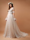 Wedding gown in bohemian style. Studio full-length portrait of a beautiful happy bride in effortless white wedding dress with long