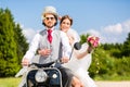 Bridal pair driving motor scooter wearing gown and suit Royalty Free Stock Photo