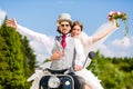 Bridal pair driving motor scooter wearing gown and suit Royalty Free Stock Photo