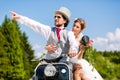 Bridal pair driving motor scooter wearing gown and suit Royalty Free Stock Photo