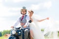 Bridal pair driving motor scooter wearing gown and suit Royalty Free Stock Photo
