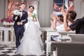 Wedding guests applauding for newlywed couple holding flowers in church