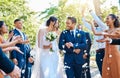 Wedding guests throwing rose petals confetti tradition over bride and groom on their special day. Newlywed couple