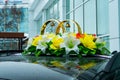 Wedding rings among flowers on the top of a wedding car