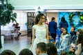 A bride model demonstrates a white wedding dress to guests