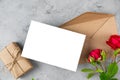 Wedding invitation. Blank greeting card with red rose flowers and gift box on gray background. Mock up. Flat lay. Royalty Free Stock Photo