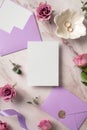 Wedding invitation card mockup, violet envelopes, gold rings, roses flowers on marble background. Flat lay, top view, copy space Royalty Free Stock Photo