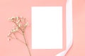 Wedding invitation or greeting card mockup with a white satin ribbon and a flower on a pink background Royalty Free Stock Photo