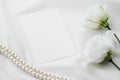 Wedding invitation, white rose flowers and pearls on silk fabric as bridal flatlay background, blank paper greeting card Royalty Free Stock Photo