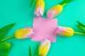 Wedding mockup with pink paper list and tulip flowers on green table top view. Beautiful floral pattern. Flat lay style Royalty Free Stock Photo