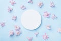 Wedding mockup with white paper list and pink flowers on blue background top view. Beautiful floral pattern. Flat lay style.