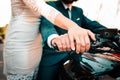 Wedding, newlyweds. A man and a woman in wedding attire hold on to a motorcycle handle, showing off their engagement rings. Hands Royalty Free Stock Photo