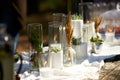 Wedding party banquet outdoors in forest. Dining table decorated in boho style with candles, white cloth, flowers