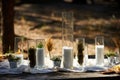 Wedding party banquet outdoors in forest. Dining table decorated in boho style with candles, white cloth, flowers