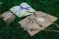 Wedding or party decorative envelopes lie on the green grass. Ivory, brown and violet colours. Strings and lavender. Rustic