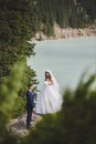 Beautiful wedding photo on mountain lake. Happy Asian couple in love, bride in white dress and groom in suit are photographed agai