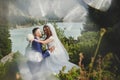 Beautiful wedding photo on mountain lake. Happy Asian couple in love, bride in white dress and groom in suit are photographed agai