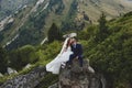 Beautiful wedding photo on mountain lake. Happy Asian couple in love, bride in white dress and groom in suit are photographed agai