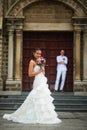 Wedding photo with bride and groom. Beautiful young bride posing on the background of the groom and the Catholic Church Royalty Free Stock Photo