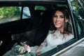 Wedding photo of the bride who is sitting in the car with a bouquet of flowers Royalty Free Stock Photo