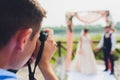 Wedding photographer takes pictures of bride and groom in city. wedding couple on photo shoot. photographer in action. Royalty Free Stock Photo