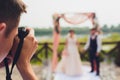 Wedding photographer takes pictures of bride and groom in city. wedding couple on photo shoot. photographer in action. Royalty Free Stock Photo