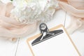 Wedding planner clipboard mockup with peonies and beige cloth on white rustic wooden table. Wedding preparation checklist concept