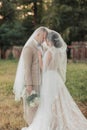 Wedding portrait of the bride and groom. Happy bride and groom gently hug each other under the veil, pose and kiss. Royalty Free Stock Photo