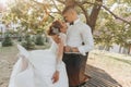 Wedding portrait. A groom in a black suit and a blonde bride in a dress and sneakers Royalty Free Stock Photo