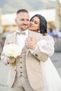 Wedding portrait of smiling newlyweds. A stylish groom in a beige suit and a cute brunette bride in a white dress are tenderly Royalty Free Stock Photo