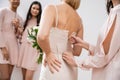wedding preparations, bridesmaid zipping wedding dress