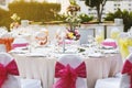 Wedding reception dinner table setting with flower decoration and white cover chairs pink sash