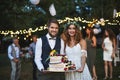 Bride and groom holding a cake at wedding reception outside in the backyard. Royalty Free Stock Photo