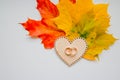 Wedding ring on wooden heart on autumn leaves background. Close-up view of golden wedding rings. Autumn wedding card or Royalty Free Stock Photo
